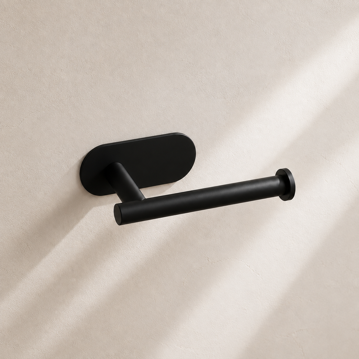 Matte black self-adhesive toilet paper holder in warm neutral studio setting